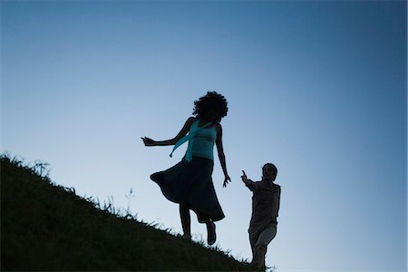 silhouette person running - Young woman playfully running away from man in pursuit Foto de stock - Sin royalties Premium, Código: 695-05770873