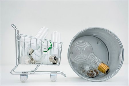 Shopping cart containing energy efficient light bulbs next to garbage can containing conventional light bulbs Stock Photo - Premium Royalty-Free, Code: 695-05770899