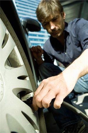 Man inflating vehicle tire using air pump hose Foto de stock - Sin royalties Premium, Código: 695-05771002