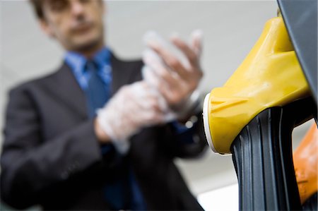 petrol pump man - Man putting putting on disposable gloves preparing to refuel vehicle Stock Photo - Premium Royalty-Free, Code: 695-05771063