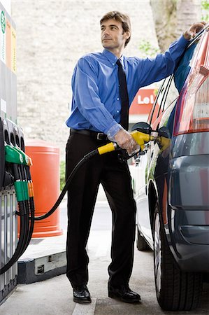 Well-dressed man refueling vehicle at gas station Stock Photo - Premium Royalty-Free, Code: 695-05771076