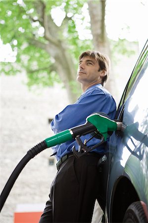 Well-dressed man refueling vehicle at gas station Stock Photo - Premium Royalty-Free, Code: 695-05771079