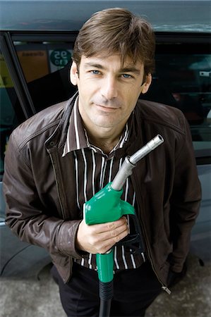 Man at gas station holding gas nozzle Stock Photo - Premium Royalty-Free, Code: 695-05771083