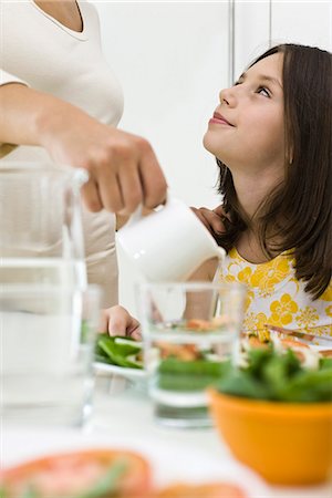 serving food - Girl sitting at table looking up at mother serving food Stock Photo - Premium Royalty-Free, Code: 695-05771170