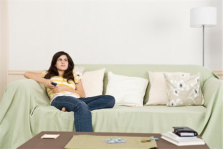 Teenage girl with remote control contemplatively looking away Stock Photo - Premium Royalty-Free, Code: 695-05771203