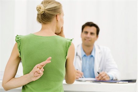 deception - Female patient with hand behind back crossing fingers, speaking with doctor Stock Photo - Premium Royalty-Free, Code: 695-05771267