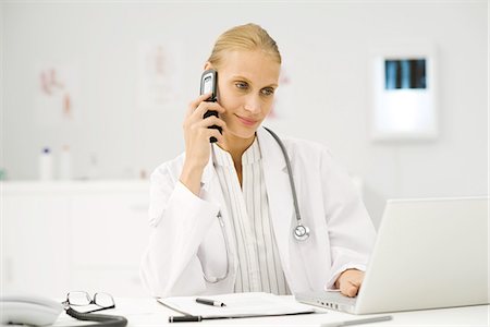 Female doctor multi-tasking at desk Stock Photo - Premium Royalty-Free, Code: 695-05771275