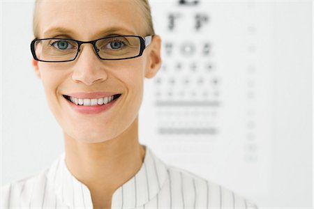 eye exam - Young woman wearing glasses, eye chart in background, portrait Stock Photo - Premium Royalty-Free, Code: 695-05771272