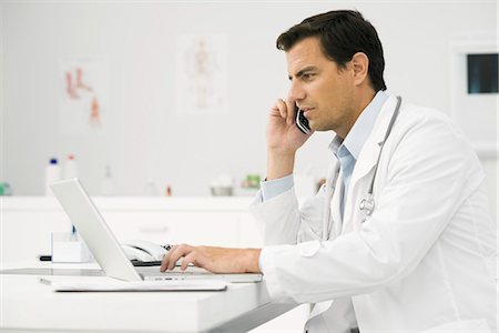 simsearch:695-05771285,k - Doctor on phone call using laptop computer Foto de stock - Royalty Free Premium, Número: 695-05771284