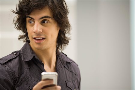 distraction - Young man text messaging, looking away in distraction Stock Photo - Premium Royalty-Free, Code: 695-05771400