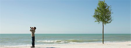 simsearch:633-05401630,k - Garçon debout sur la plage, à la recherche en mer avec des jumelles Photographie de stock - Premium Libres de Droits, Code: 695-05771520