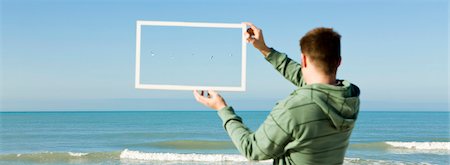 fly, concept - Gulls flying above sea framed in picture frame held aloft by man on beach Stock Photo - Premium Royalty-Free, Code: 695-05771523