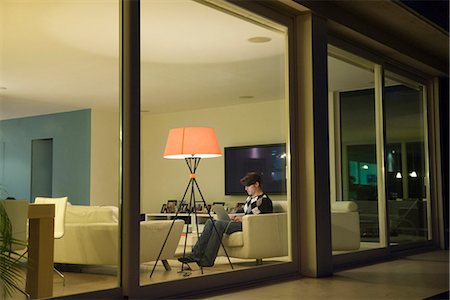 Man using laptop in living room, viewed through window Foto de stock - Sin royalties Premium, Código: 695-05771870