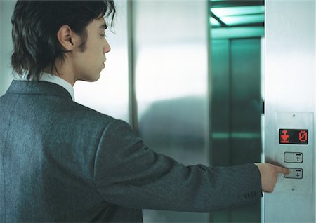 pushing door - Young man in suit pushing button for elevator Stock Photo - Premium Royalty-Free, Code: 695-05771900