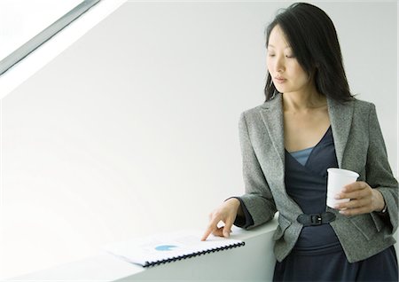 elegant asian woman reading - Businesswoman looking at report and holding cup Stock Photo - Premium Royalty-Free, Code: 695-05771959