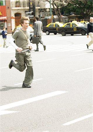 Jeune homme traversant la rue de ville Photographie de stock - Premium Libres de Droits, Code: 695-05772143