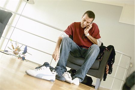 flat shoes - Man putting on shoes and talking on phone Stock Photo - Premium Royalty-Free, Code: 695-05772186