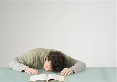 Young man with head on table in front of open notebook Stock Photo - Premium Royalty-Free, Code: 695-05772320