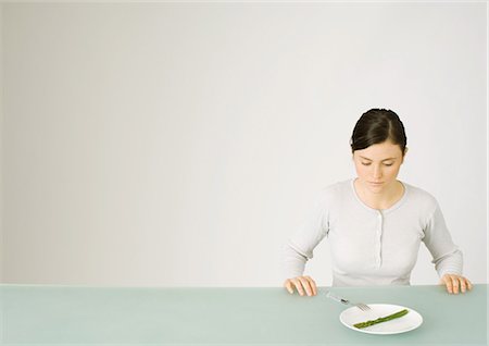 simsearch:400-04402342,k - Young woman looking down at single asparagus on plate Stock Photo - Premium Royalty-Free, Code: 695-05772322