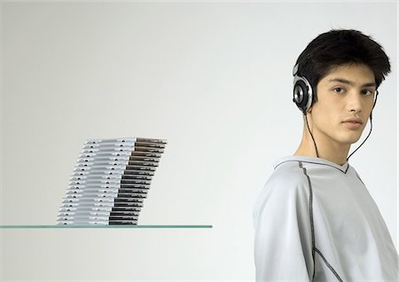 Young man listening to headphones, next to stack of cds Stock Photo - Premium Royalty-Free, Code: 695-05772336