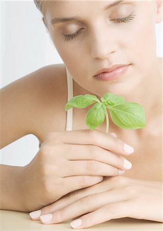 Woman smelling sprig of basil Stock Photo - Premium Royalty-Free, Code: 695-05772357