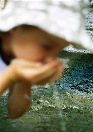 Girl drinking water from cupped hands Stock Photo - Premium Royalty-Free, Code: 695-05772523