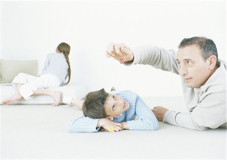 Man and son playing with dice on floor Stock Photo - Premium Royalty-Free, Code: 695-05772644