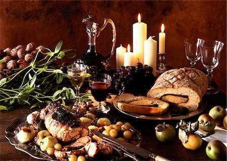 Dishes of meats, fruits and vegetables, with carafe of wine and candles in background Fotografie stock - Premium Royalty-Free, Codice: 695-05772883