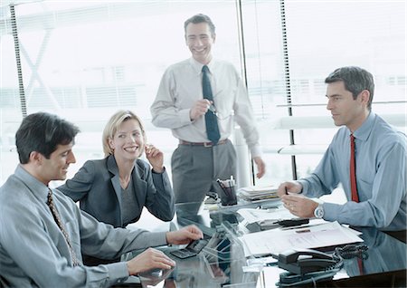 Business associates around desk, one looking at calculator Stock Photo - Premium Royalty-Free, Code: 695-05772934