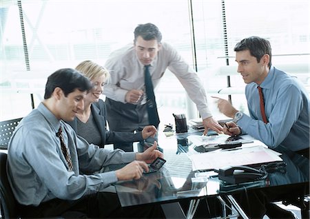 Business associates working together at desk, one using calculator Stock Photo - Premium Royalty-Free, Code: 695-05772933