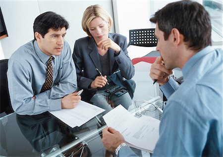 Two businessmen and a businesswoman sitting at desk Stock Photo - Premium Royalty-Free, Code: 695-05772941