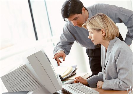 Businessman and businesswoman looking at computer screen Stock Photo - Premium Royalty-Free, Code: 695-05772954