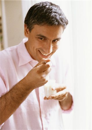 Man eating yogurt, portrait, blurred Fotografie stock - Premium Royalty-Free, Codice: 695-05773021