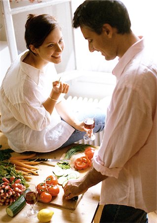 Man chopping vegetables on table, woman sitting on table, holding glass Foto de stock - Sin royalties Premium, Código: 695-05773041