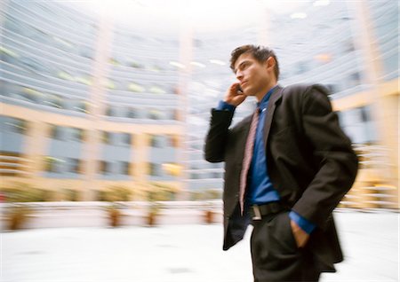 picture of person talking on string telephone - Businessman talking on cell phone, outside, building in background, blurred. Stock Photo - Premium Royalty-Free, Code: 695-05773227