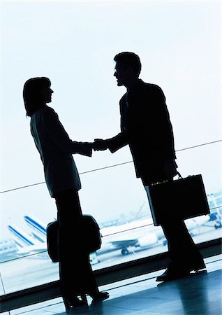 Businessman and businesswoman shaking hands in airport, silhouette. Stock Photo - Premium Royalty-Free, Code: 695-05773246