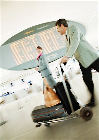 simsearch:695-03388701,k - Businessman and businesswoman walking through airport terminal, blurred. Stock Photo - Premium Royalty-Free, Code: 695-05773276