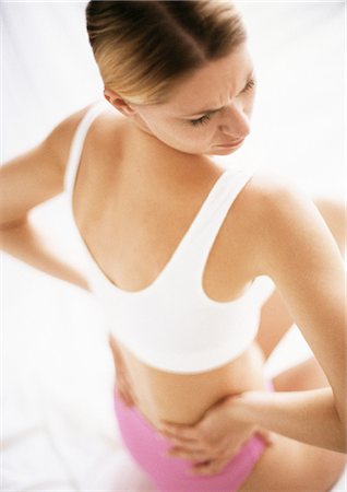 Woman in underwear holding waist, looking over shoulder, rear view. Stock Photo - Premium Royalty-Free, Code: 695-05773372