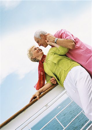 Mature couple smiling at each other, leaning on rail of boat Stock Photo - Premium Royalty-Free, Code: 695-05773383
