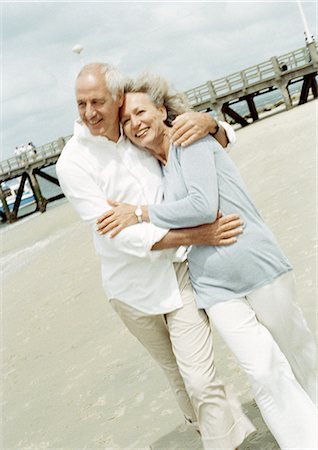 Mature couple walking with arms around each other on the beach Stock Photo - Premium Royalty-Free, Code: 695-05773404