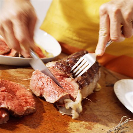 Close-up of hands cutting roast beef Stock Photo - Premium Royalty-Free, Code: 695-05773488