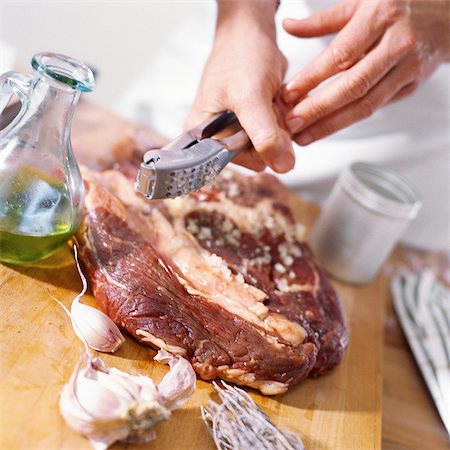 people eating raw meat - Close-up of ribeye steak being prepared with crushed garlic Stock Photo - Premium Royalty-Free, Code: 695-05773491