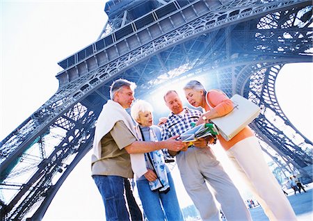senior couple looking at map - France, Paris, group of mature tourists examining a map in front of Eiffel Tower, low angle view Stock Photo - Premium Royalty-Free, Code: 695-05773698