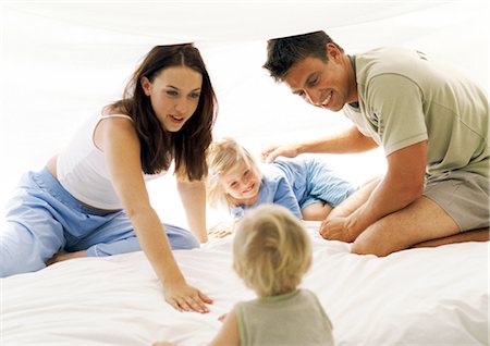 family playing backlight - Parents and two small children on bed, smiling Stock Photo - Premium Royalty-Free, Code: 695-05773993