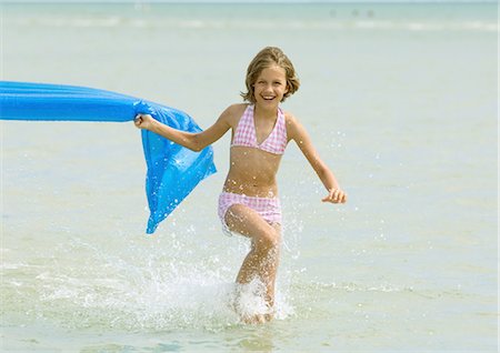 Girl running in surf with air mattress Stock Photo - Premium Royalty-Free, Code: 695-03374017