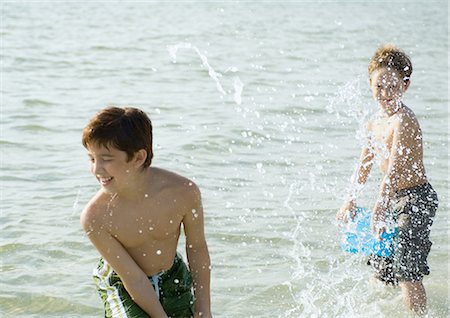 Boys splashing in ocean with buckets Stock Photo - Premium Royalty-Free, Code: 695-03374045
