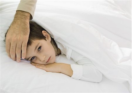 father sick child - Child lying in bed with father's hand on forehead Stock Photo - Premium Royalty-Free, Code: 695-03374389