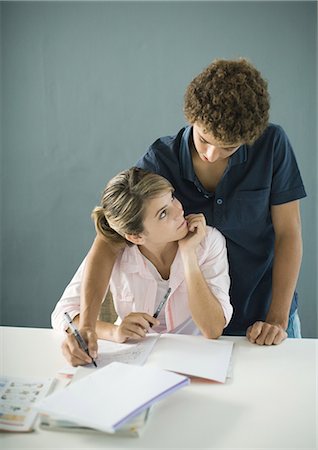 Teenage boy and girl doing homework together, boy reaching over girl's shoulder Stock Photo - Premium Royalty-Free, Code: 695-03374382