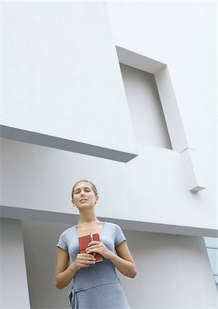 simsearch:695-03373539,k - Woman standing in front of building, holding closed book, eyes shut, low angle view Stock Photo - Premium Royalty-Free, Code: 695-03374415