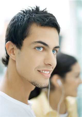 Two teenage friends sharing earphones, focus on young man in foreground Stock Photo - Premium Royalty-Free, Code: 695-03374443
